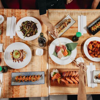 People sharing assorted dishes around a table, overhead view.