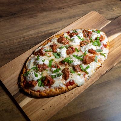 Flatbread pizza with melted cheese, meatballs, and fresh basil.