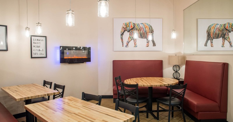 Interior with wooden tables, red booth seating, and colorful elephant artwork