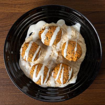 Falafel balls on a bed of hummus.