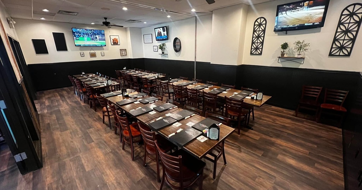 Dining room with neatly arranged tables, chairs, and wall televisions
