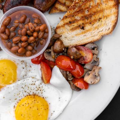 Two fried eggs with beans, toast, mushrooms, and cherry tomatoes.