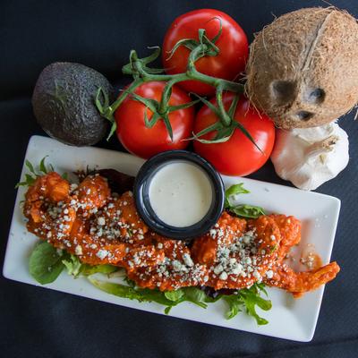 Buffalo Shrimp garnished with crumbled blue cheese and served with a dipping sauce.