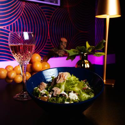 Mixed greens salad with cheese and chunks of tuna paired with a glass of rose.