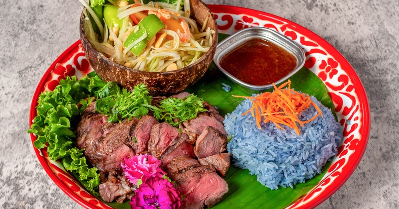 "Crying Tiger" steak served with butterfly pea flower rice, papaya salad and a dip