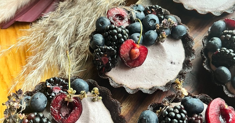 Blackberry mousse tartlets with fresh cherries, blueberries, and blackberries in a chocolate crust.