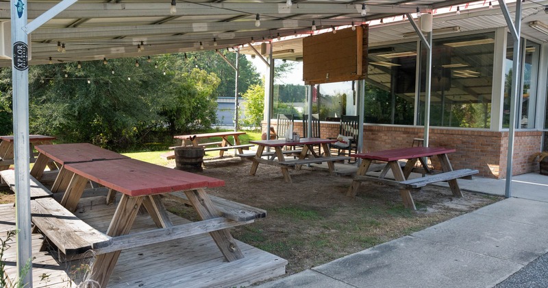 Exterior, covered seating area, wooden benches and tables, lanterns on the ceiling