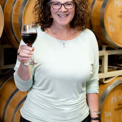 A person holding up a glass of red wine.