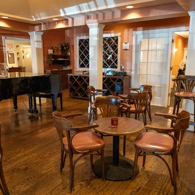 Elegant interior, tables and seats, wine racks, a piano in the middle of the room.