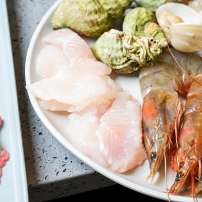 Plate of assorted raw seafood, prepared for cooking in a hot pot.
