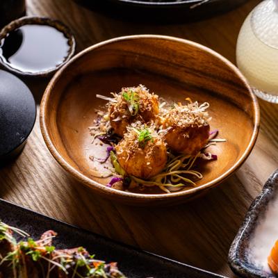 Takoyaki fried octopus balls with shredded cabbage, toppings, and a cup of sauce.