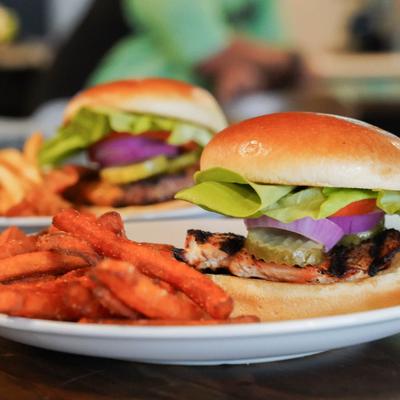 Two burgers with vegetables alongside sweet potato fries.
