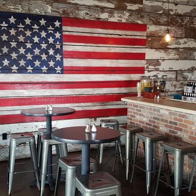 Rustic interior design, bar and seating area, large mural US flag on a wall.