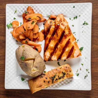 Bourbon salmon served with focaccia, baked potato, and carrots.