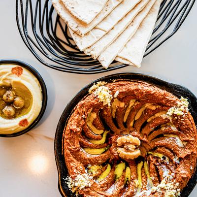 Muhamara dish, hummus, and pita, top view.