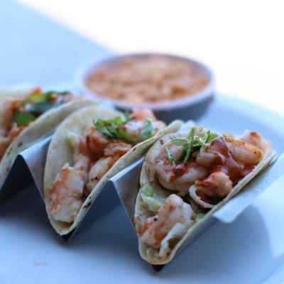 Shrimp tacos topped with sauce and cilantro, served with rice.