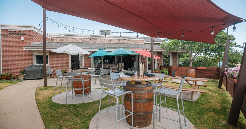 Exterior, patio area, barrel tables with tall bar chairs and shade sail