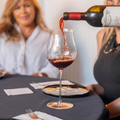 Wine service, a server pours a glass of wine for a guest at table.