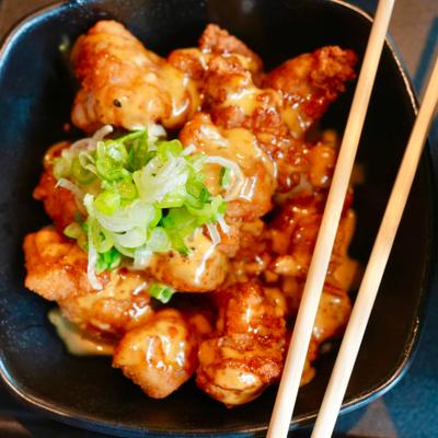 Crispy fried chicken bites drizzled with creamy sauce and topped with scallions.