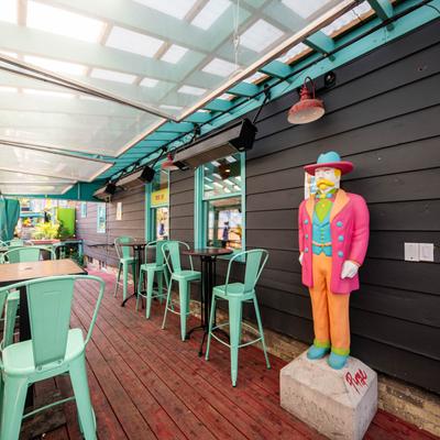 Exterior, covered patio seating area, and a colorful statue.