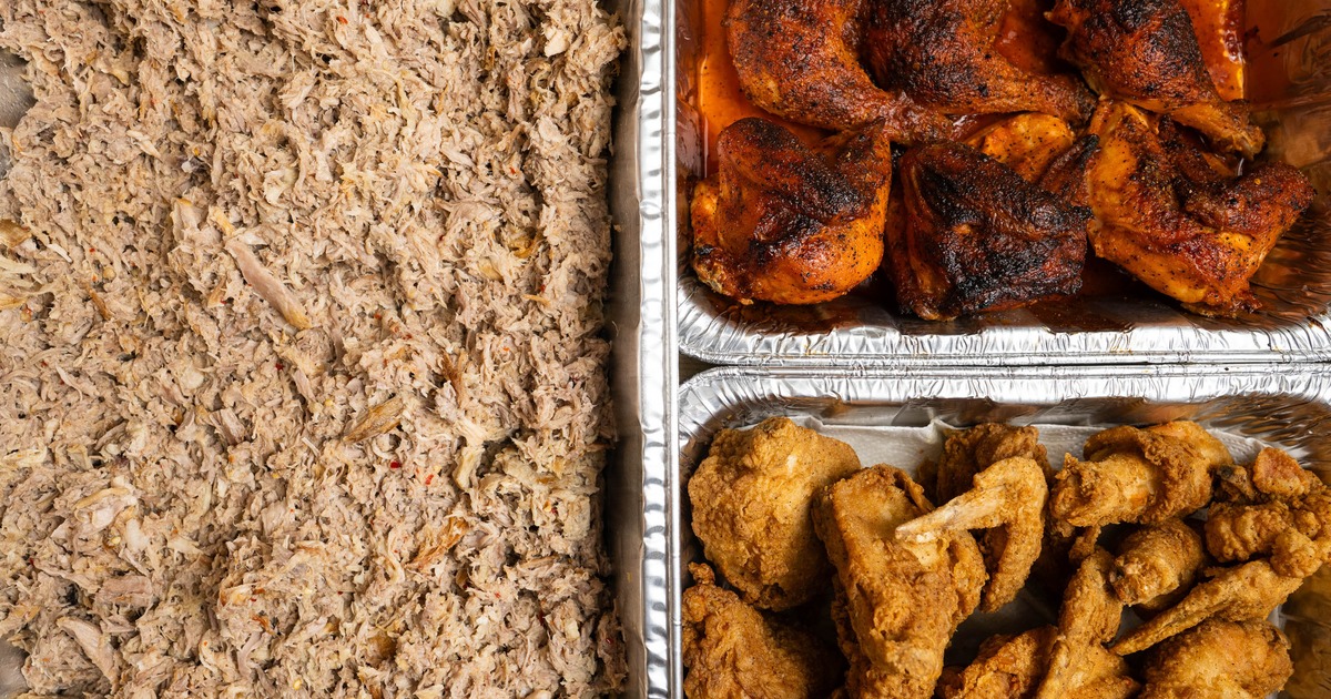 BBQ catering spread with aluminum trays containing shredded pork and ribs