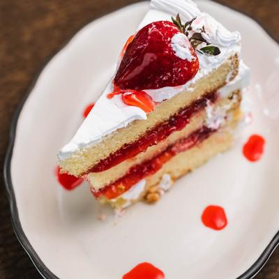 Close up of a strawberry short cake slice on white plate.