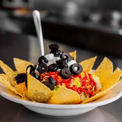 Taco salad with tortilla chips, cheese, lettuce, olives, and sour cream.