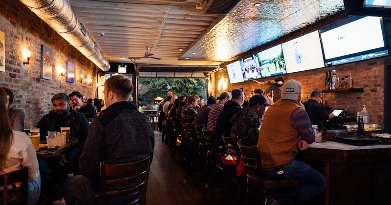 Interior, bar area with guests sitting at the bar counter and tables