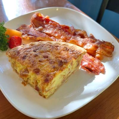 Breakfast quiche served with crispy bacon strips.
