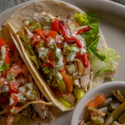 Grilled chicken tacos with peppers served with green beans.