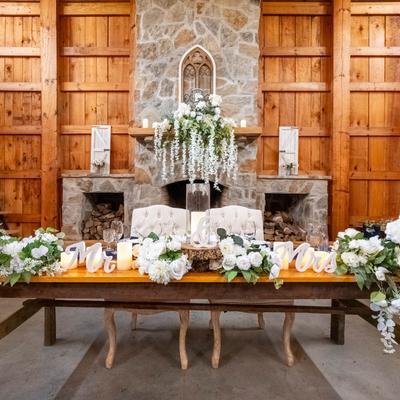 Newlywed table with flowers, Mr and Mrs sign, and a stone fireplace behind.