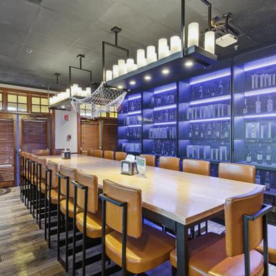 Long table with leather chairs under modern lights, a modern bar and tasting room.