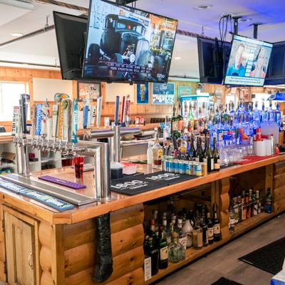 Wooden bar with liquor bottles, beer taps, and mounted TVs.