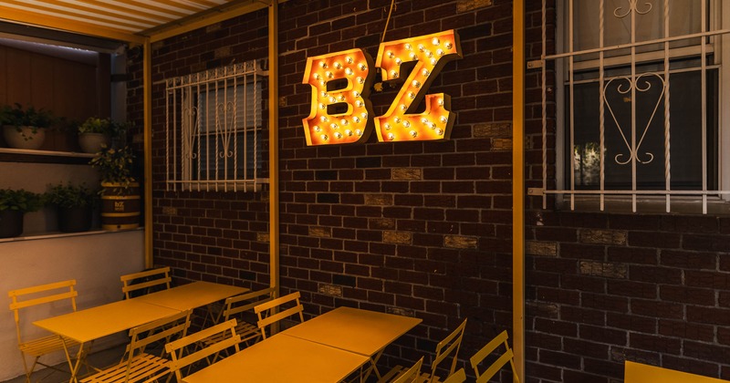 Patio, tables and chairs near logo on the wall