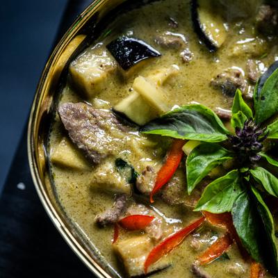 Green curry with basil on dark table, close up.