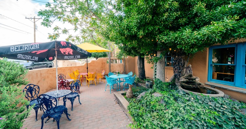 Outdoor patio with colorful tables, chairs, umbrellas, and greenery
