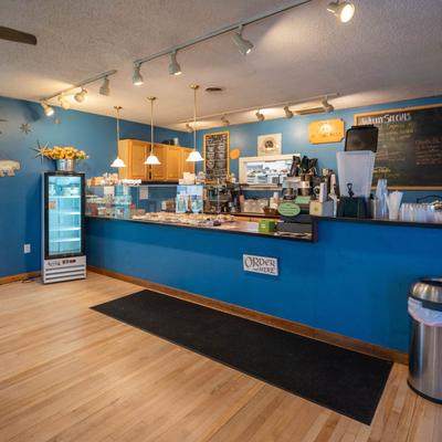 Interior space with blue walls and a wooden counter displaying pastries.