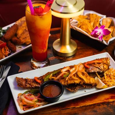 Red Snapper served with tortilla chips, fried plantains, and a layered cocktail.