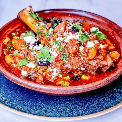 Braised lamb shank in tomato sauce with vegetables and herbs.