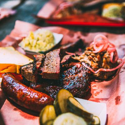 BBQ platter with brisket, sausage, and pickles.