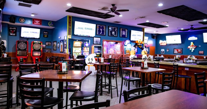Interior of a sports bar with tables, arcade machines and TVs