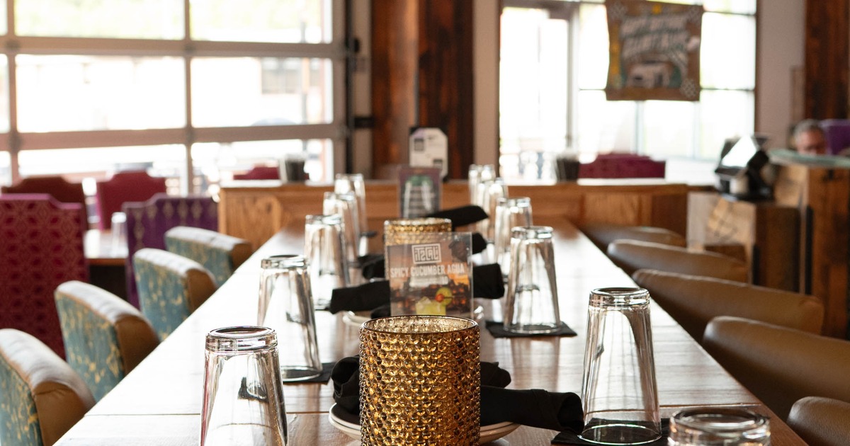 Restaurant dining room with a long set wooden table, amber candleholder