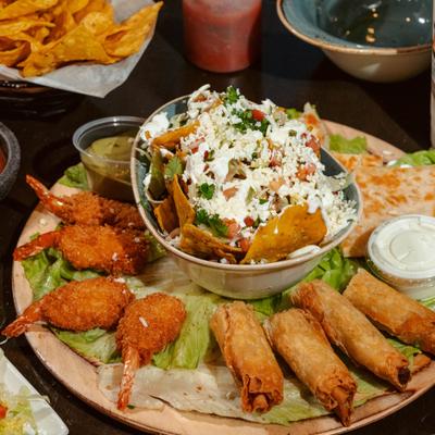 Sampler Plater with loaded nacho chips, quesadilla, taquitos, breaded shrimp and dips.