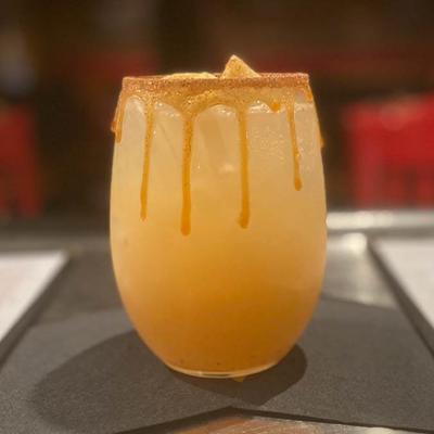 A yellow cocktail drink with dripping rim, side view.