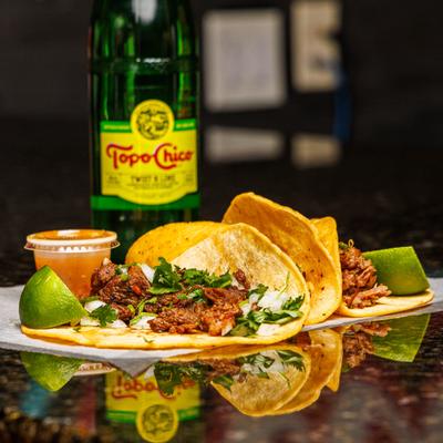 Portion of tacos served with condiments and a bottle of soda.