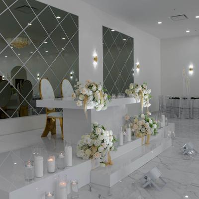 Venue's head table on a white platform with floral arrangements and candles.