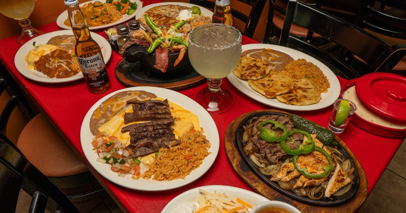 Various Mexican dishes and drinks spread across a red table