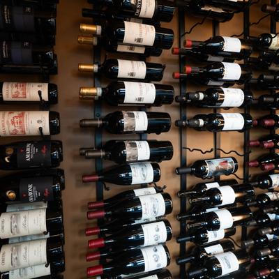 Wall-mounted metal wine rack system holding numerous bottles of wine.
