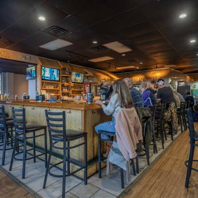 A bar with guests sitting and eating and drinking.