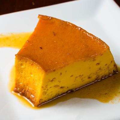 A slice of caramel custard dessert on a white plate.